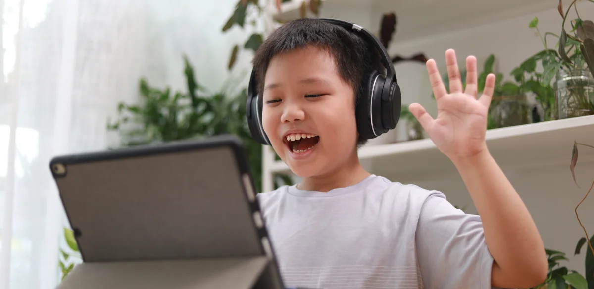 An elementary student wearin a blakc pair of headphones